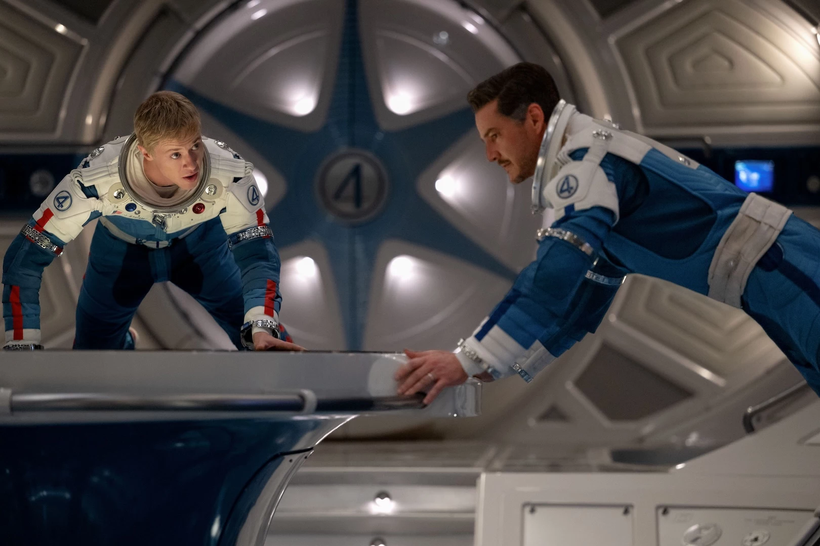 Dos astronautas interactúan en una nave espacial futurista.