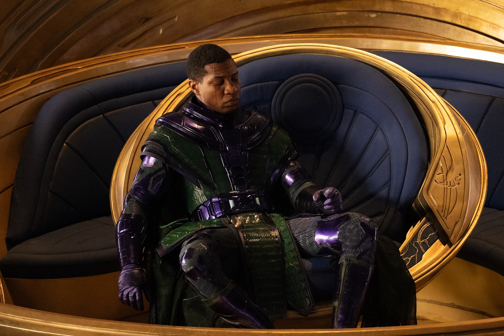Persona en traje futurista sentado en trono dorado.