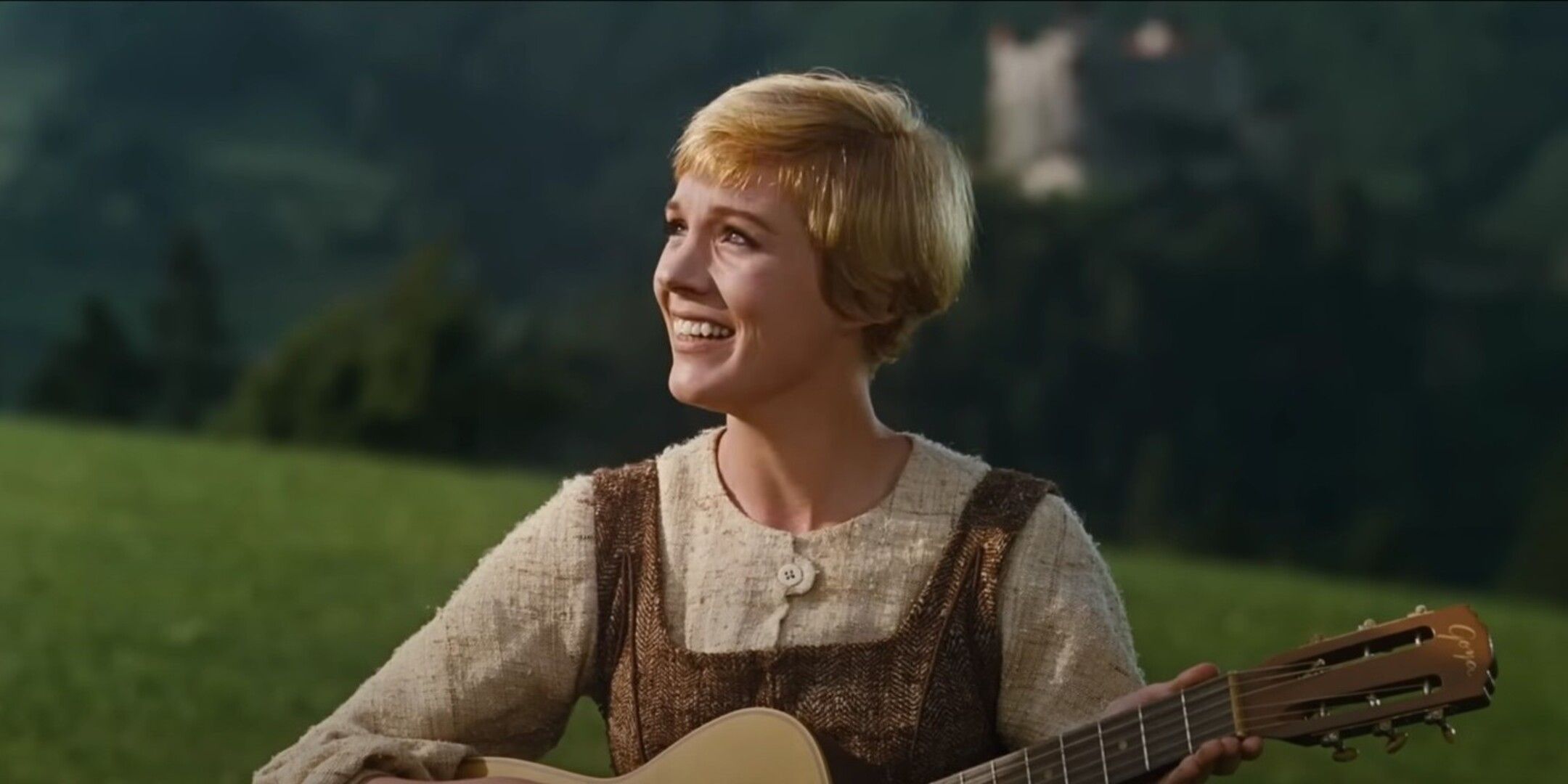 Persona sonriente tocando guitarra en campo
